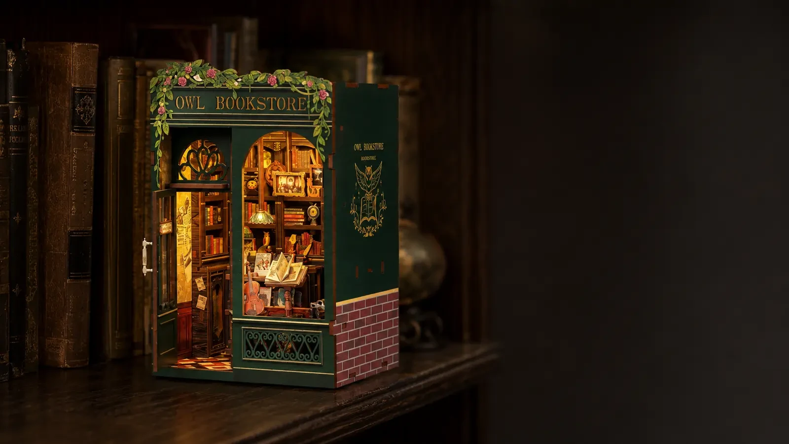 Owl Bookstore DIY Book Nook Kit with warm touch-activated LED lighting on a dark bookshelf.